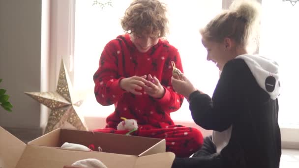 Los niños en pijama desempaquetan juguetes de Navidad, bolas de Año Nuevo. Preparativos de Navidad, Nochebuena, familia feliz — Vídeos de Stock