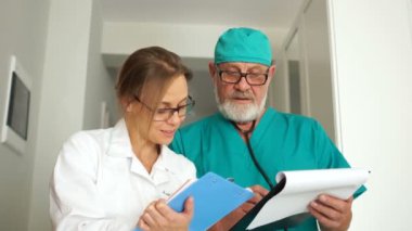 Yaşlı bir doktor ve bir bayan asistan kliniğin koridorunda yürüyorlar. Bir erkek yön tarif eder ve bir kadın da randevusunu hastanın tıbbi geçmişine yazar. Sağlık personeli