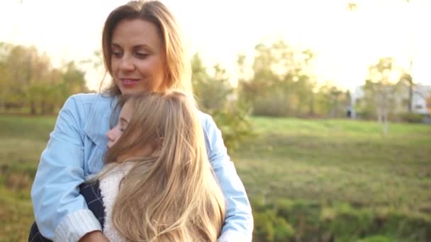 Chica adolescente abraza a su hermosa madre joven en el parque de la ciudad de otoño. Madre e hija, día de las madres — Vídeo de stock