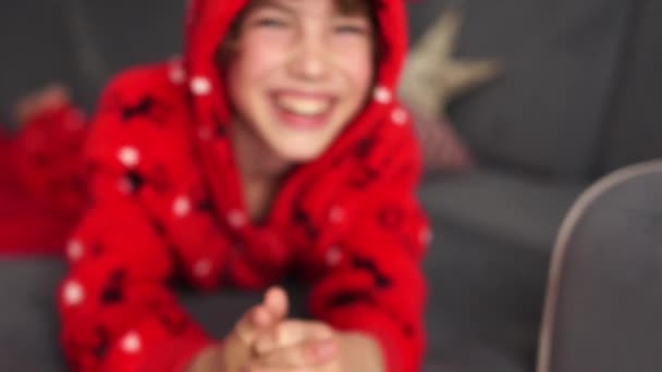 Bliski portret przystojnego niebieskookiego chłopca w czerwonej piżamie z jeleniem w ubranym kapturze. Święta, Święta Bożego Narodzenia — Wideo stockowe