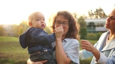 İki genç anne bebeği ile yaz aylarında parkta yürüyorlar. LGBT lezbiyen çift. Aile ve sağlıklı yaşam kavramı