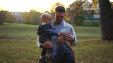 Genç ve çekici bir baba iki çocukla parkta yürüyor. Bir adam küçük bir oğlanı kollarında tutuyor ve genç kızına sarılıyor. Babalar Günü
