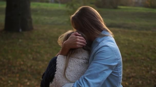 Abendspaziergang einer jungen Mutter und ihrer Schulmädchen-Tochter. Mädchen, die sich zärtlich im Park umarmen, Mutterliebe, Muttertag, Rückansicht — Stockvideo