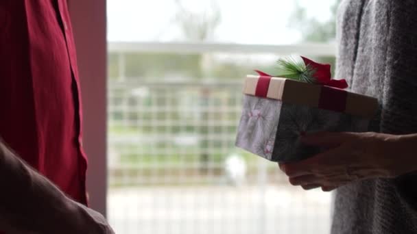 Retrato cercano hombre y mujer maduros desean que el otro Feliz Navidad. Un hombre le da a una mujer un regalo, un par de besos gentiles. Personas mayores en el hogar de ancianos celebran la Navidad — Vídeo de stock