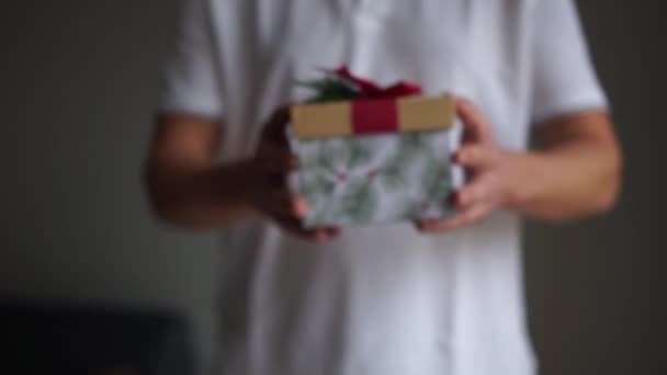 Рождественский подарок в красивой упаковке в мужские руки. Счастливого Рождества. Мужчина держит в руке подарочную коробку в знак дарения — стоковое видео