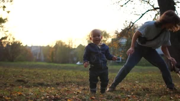 Jonge moeder en baby in het najaarspark 's avonds spelen met een hond. Familie wandelen met een huisdier — Stockvideo