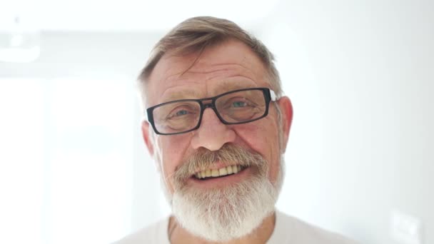 Close portraits of a happy laughing elderly man with glasses and a beard. Good grandfather, fathers day — Stock Video