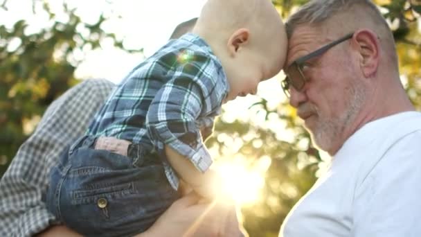 Cerca del puerto, tres generaciones de hombres de la misma familia en el parque al atardecer. Deslumbramiento del sol, familia feliz, día del padre — Vídeos de Stock