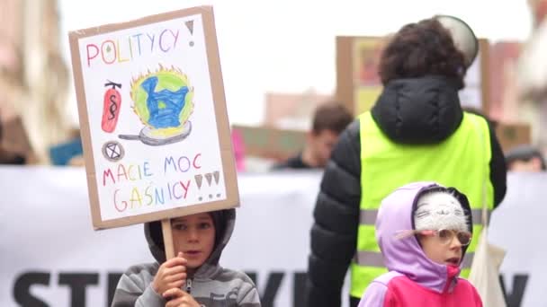 Wroclaw, Polônia 29 de novembro de 2019. Greve climática. Uma criança segura um cartaz com a inscrição em polonês - Política, você pode colocar para fora. Adultos no fundo cantam em um microfone e alto-falante — Vídeo de Stock