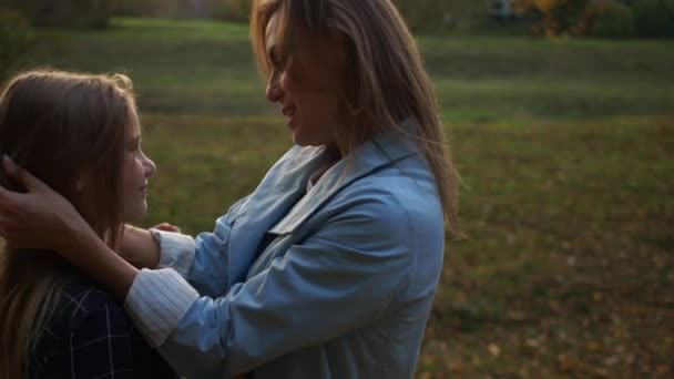 Ημέρα Μητέρας. Οπίσθια όψη, δυναμικό βίντεο, κλειστό υπαίθριο πορτρέτο της αγκαλιασμένης μαμάς και της κόρης αγκαλιάζει το βράδυ το σούρουπο σε ένα πάρκο της πόλης — Αρχείο Βίντεο