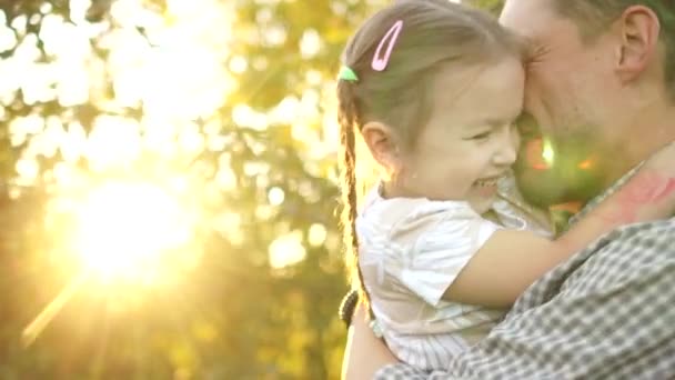 Portrait of a happy young father with his five-year-old daughter in his arms in an apple orchard against the backdrop of the setting sun. Happy family vacation Royalty Free Stock Video