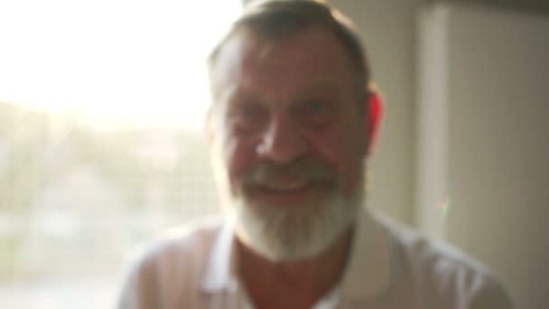 Портрет со светом солнца пожилого счастливого пенсионера в очках с седой бородой и белой футболкой. Счастливый выход на пенсию — стоковое видео