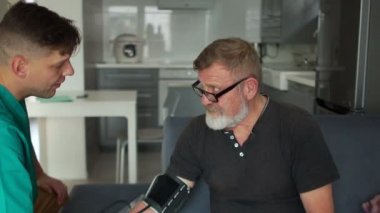 Tansiyon ölçümü. Yaşlı bir hasta ve genç bir doktor evde bir hastada tonometre ile kan basıncını ölçme işlemi sırasında. Yüksek tansiyon, sağlık konsepti