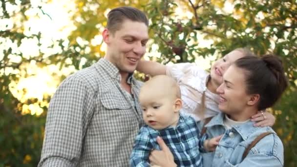 Mari, femme, frère et sœur se blottissent dans le parc d'automne sur fond de coucher de soleil. Happy Family Weekend. Portrait rapproché d'une grande famille de quatre personnes — Video