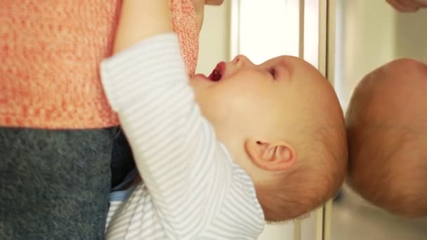 Un bébé d'un an et demi pleure debout près de sa mère. L'enfant demande des stylos. Fâché enfant en colère. Mère et bébé — Video