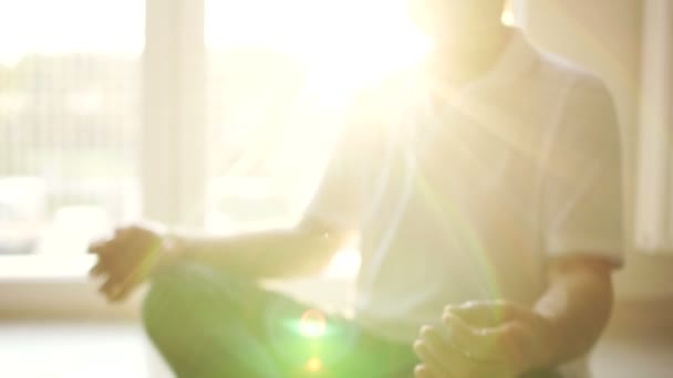 Meditation and yoga. Spiritual practice, an elderly yogi sits on the floor in a lotus position. Sun glare — ストック動画