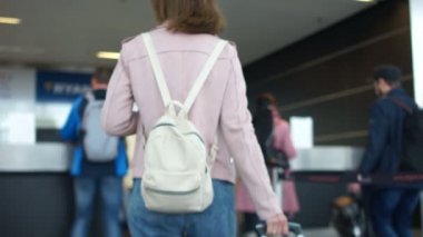 Güzel genç turist kızla sırt çantası ve Bagaj check-in kontuarında uluslararası havaalanında devam, bir subay pasaportu veren ve onu yatılı için bekleyen geçmek