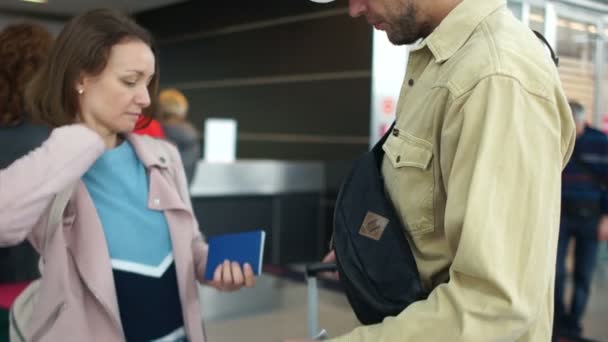 Casal estressado olhando para o cartão de embarque verificando a hora de partida em frente ao horário do avião no aeroporto — Vídeo de Stock