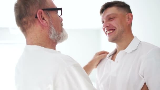 Elderly father is pleased to see his adult son. Two men are smiling, hugging and looking at each other. Good relationship, happy family Video Clip