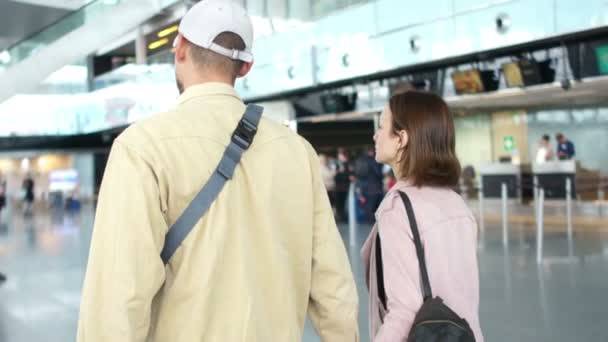Mąż eskortuje swoją żonę w samolocie, zbliżenie mężczyzny i kobiety spacerują z walizką na lotnisku. Para spóźniona na lot, odlot — Wideo stockowe