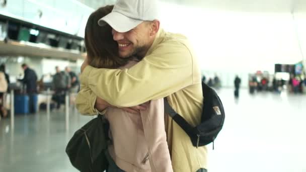 Unge man träffar en kvinna på flygplatsen. Kvinna och man kramar varandra på ett möte. Möte på flygplatsen, man och hustru — Stockvideo