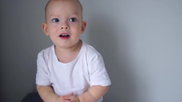 Retrato de un hermoso niño de ojos azules con una camiseta blanca. El niño aplaude, la infancia feliz, los niños emociones — Vídeos de Stock