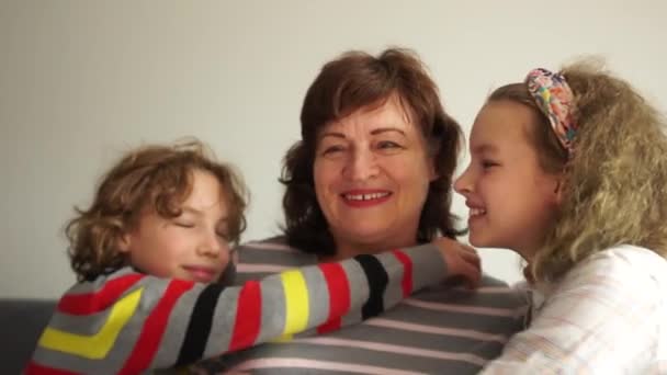 Amando a la abuela y a sus nietos. Una mujer feliz abraza a dos escolares, un niño y una niña, un hermano y una hermana. Familia feliz, retrato familiar — Vídeos de Stock
