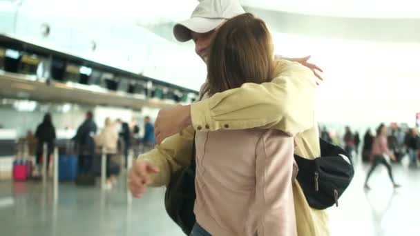 Concepto de viaje, abrazos de hombre y mujer mientras se reúnen en el aeropuerto. Amigos abrazo después de larga separación — Vídeo de stock