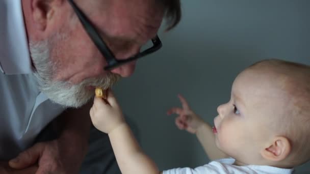 El nieto alimenta a su abuelo con galletas. Retrato cercano, buen abuelo, familia feliz — Vídeo de stock