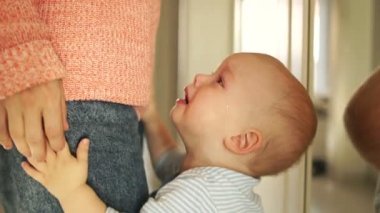 Ağlayan çocuk annesine sarılıyor, kafasını kaldırıp ona bakıyor. Bebek ağlıyor, anne aldırış etmiyor. Anneliğin psikolojik sorunları.