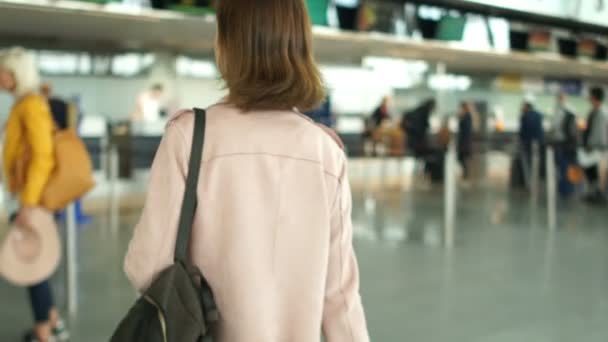 Hnědovlasá žena stojí frontu na odbavovací přepážce na letišti. Cestovní koncept — Stock video