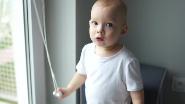 Close indoors portrait of a cute kid. The child is embarrassed looking at the camera. Happy childhood, adoption of a child — 비디오