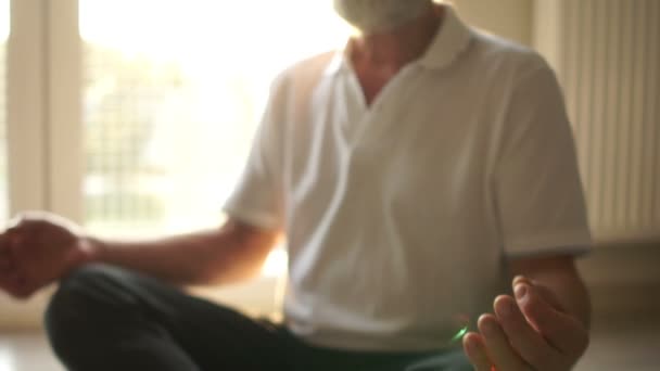 Yogi anziani, meditazione e pratica spirituale, asasasna seduto. Un uomo in posizione di loto si siede sul pavimento di fronte alla finestra — Video Stock