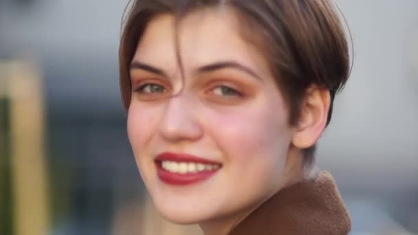 Nahporträt einer schönen, kurzhaarigen jungen Frau. lächelt das Mädchen und glättet ihre Haare. roter Lippenstift, weißzahniges Lächeln — Stockvideo