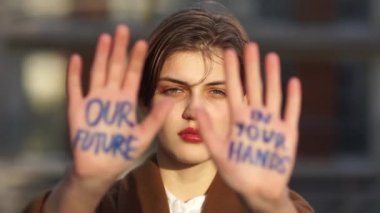 Climat strike, çevre felaketi. Avuçlarında yazı olan güzel bir öğrencinin yakın portresi. Geleceğimiz senin ellerinde. Genç kadın küresel ısınmayı protesto etti