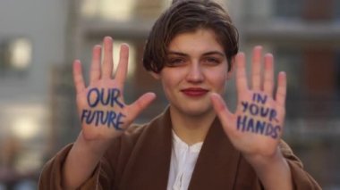İklim saldırısı. Kısa saçlı, elinde yazı olan genç bir kız. Geleceğimiz senin ellerinde. Küresel iklim değişikliği. Ellerini onun önünde uzattı.