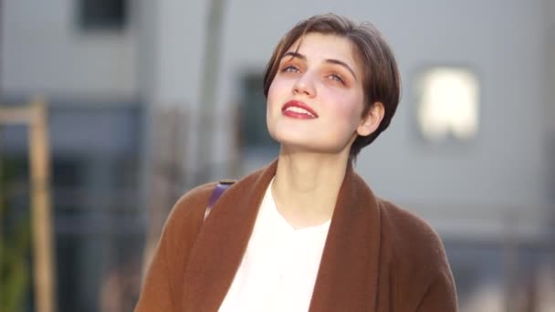 Glückliche Frau nahe Portmonee. Stadtporträt eines schönen jungen Mädchens mit Kurzhaarschnitt und braunem Mantel — Stockvideo