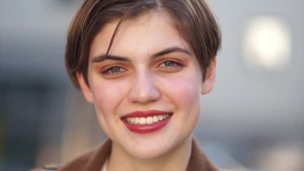 Close outdoor portrait. Happy woman. Girl with a short haircut and red lipstick on her lips is smiling — Stock Video