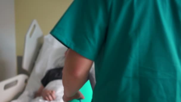 Katastrofåterställning. En ung man ligger i sängen bredvid en läkare eller sjuksköterska. Sjukhusbehandling — Stockvideo