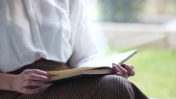 Kapanış kızı pencere pervazında otururken eski bir kitap okuyor. Mutlu kadın. — Stok video
