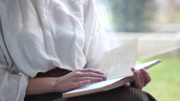 Жінка-студент у відпустці читає книгу, що сидить у вікні. Портрет милої короткошерстої дівчини — стокове відео