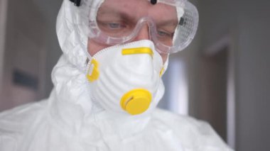 Koruyucu giysili ve maskeli bir doktor yakın portre yapmaya hazırlanıyor. Salgın tehdidi, koronavirüs tedavisi, koronavirüs aşısı.