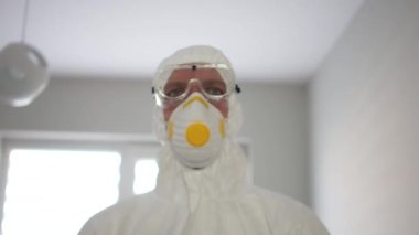 Coronavirus koruması, salgın tehdidi. Koruyucu yalıtım kıyafeti ve maskeli bir adamın yakın portresi.