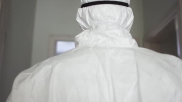 Achteraanzicht. Een arts in een beschermend pak en masker loopt een isolatiekamer binnen. Pandemische dreiging, behandeling met coronavirus, coronavirusvaccin — Stockvideo