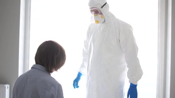 Чоловік у захисному костюмі вводить хвору жінку. Пандемічна загроза, небезпечний вірус, вакцина, концепція коронавірусу — стокове відео
