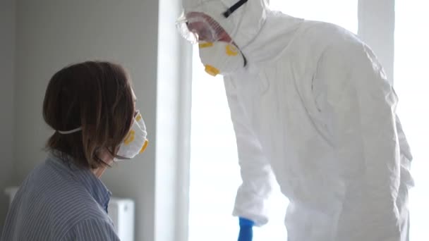 Врач в защитном костюме осматривает пациента с коронавирусом. Сияет фонариком во рту. Эпидемия коронавируса, распространение опасного вируса гриппа — стоковое видео