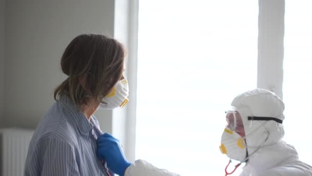 Man arts in een beschermend pak luistert naar de adem van een oudere zieke vrouw met behulp van een fonendoscoop. Gevaarlijk virus, symptomen van coronavirus — Stockvideo