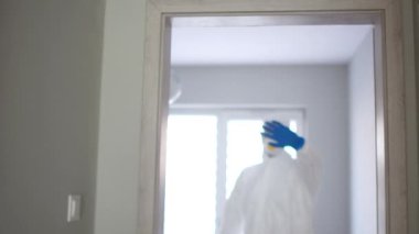 Beyaz koruyucu takım elbiseli bir adamın yakın portresi. Doktor elini öne atıyor ve jestler duruyor, giriş yok, enfeksiyon tehlikesi var. Koronavirüs salgını tehdidi