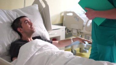 Bir kazadan sonra rehabilitasyon. Genç bir adam yatakta yatıyor, yanında bir doktor duruyor, bir hasta bir doktorla konuşuyor.