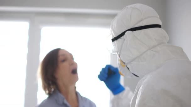 Medizinische Grenzkontrolle. Ein Mann in weißem Schutzmantel kontrolliert die ankommenden Passagiere. Die Gefahr der Ausbreitung des Coronavirus — Stockvideo